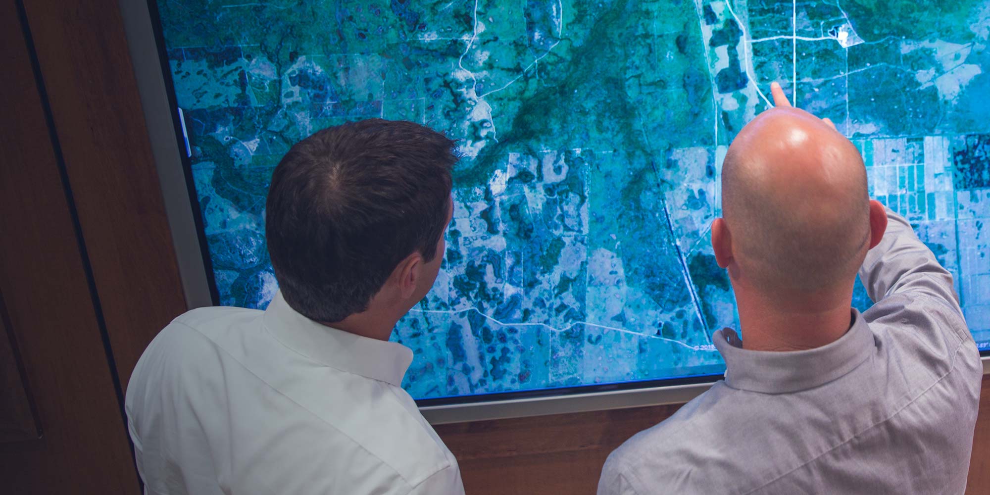 Image showing two men looking at a monitor of an aerial view of construction site.
