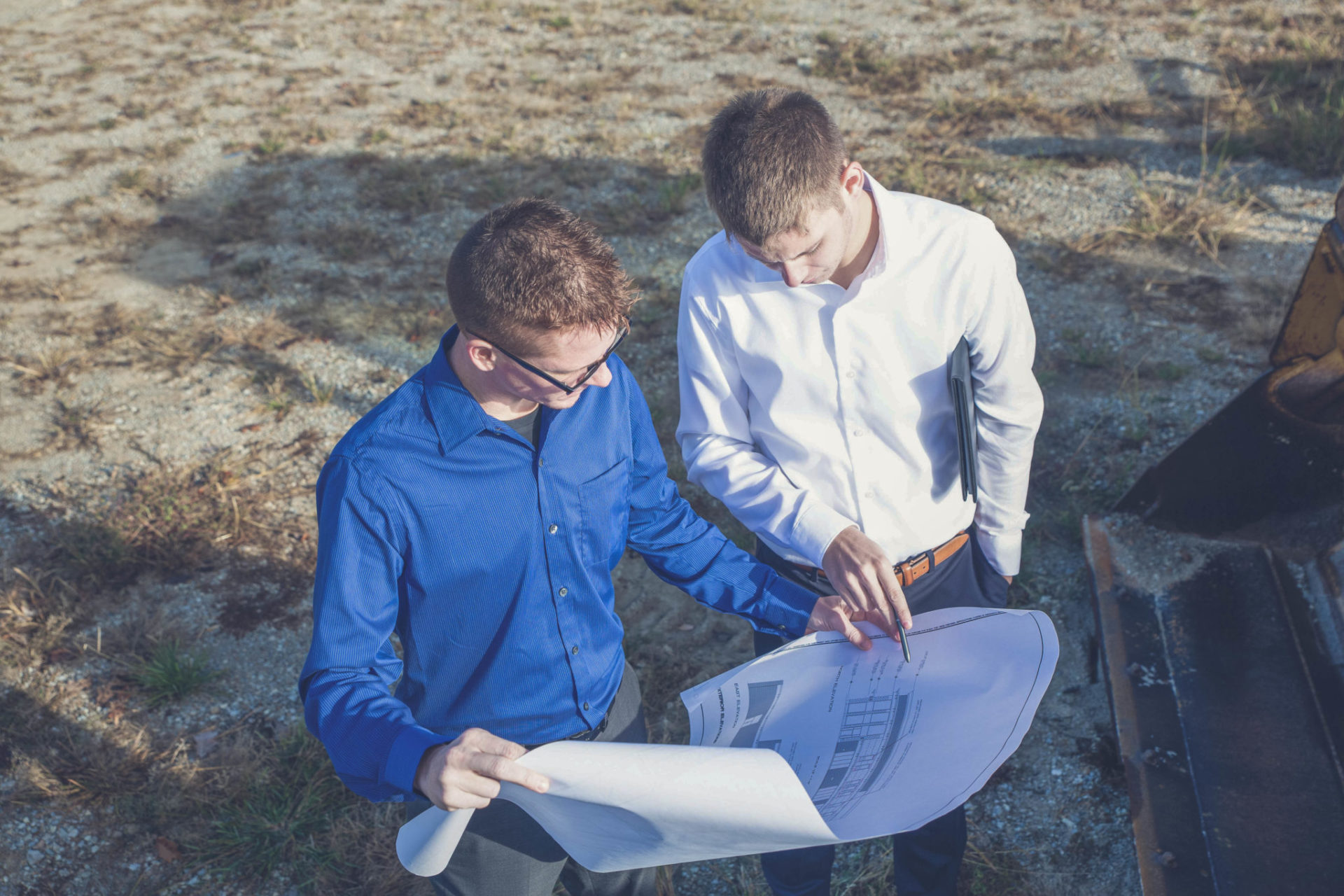 Image showing two men standing in a field reviewing construction plans.